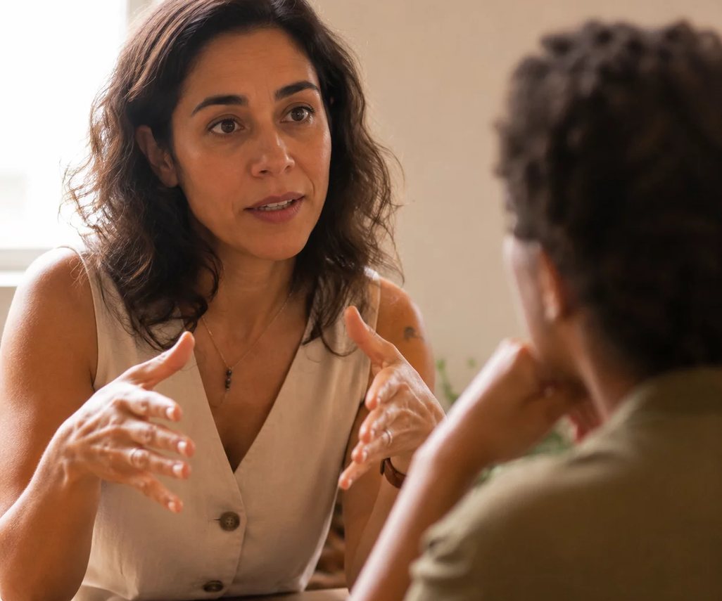 Uma pessoa sentada à mesa ergue a mão para pedir a palavra no meio da rodada